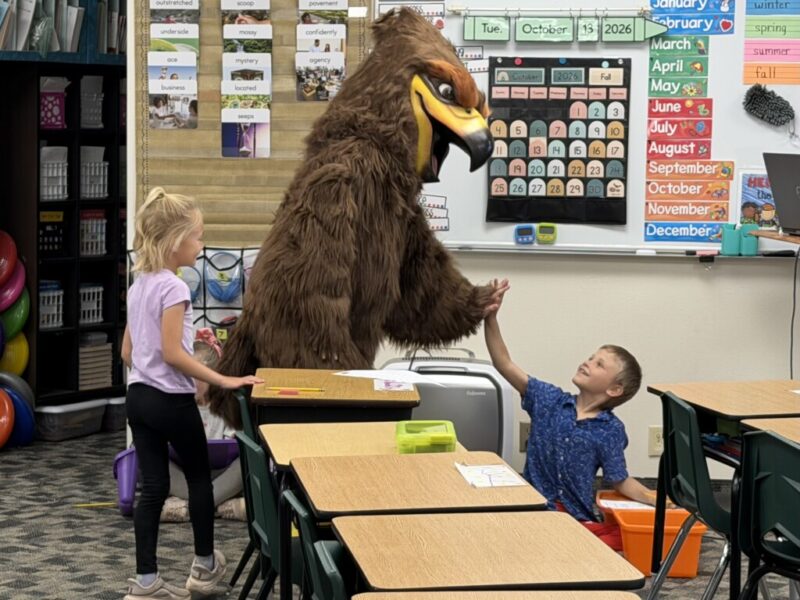 New Hawk mascot in the classroom giving student high-five
